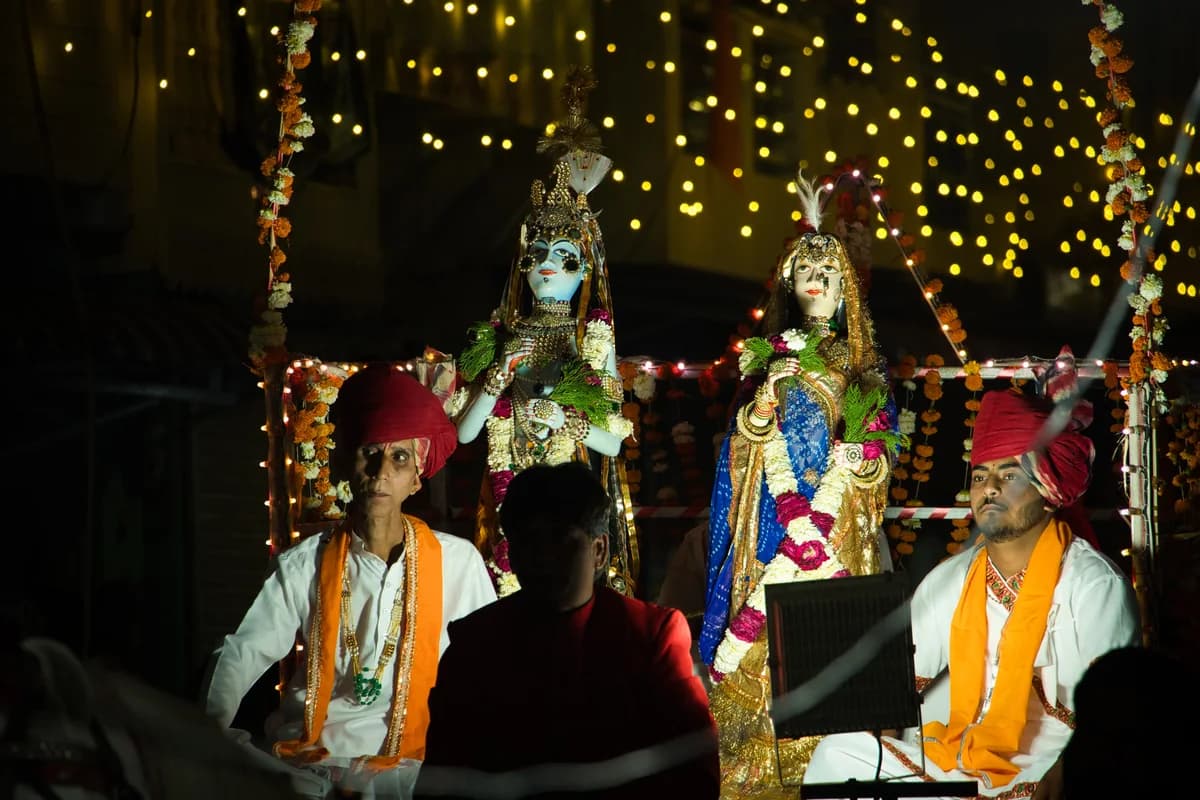 Women carrying decorated wooden idols of Gauri and Isar dressed in vibrant Rajasthani attire